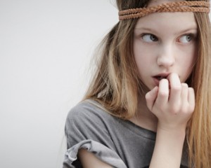 Portrait of girl wearing leather braid around head,holding feather,finger in mouth